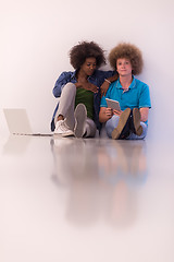 Image showing multiethnic couple sitting on the floor with a laptop and tablet