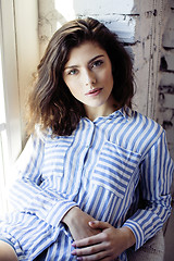 Image showing young pretty brunette woman in her bedroom sitting at window, happy smiling lifestyle people concept