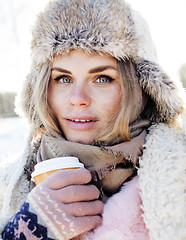 Image showing young pretty teenage hipster girl outdoor in winter snow park having fun drinking coffee, warming up happy smiling, lifestyle people concept 