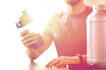 Image showing close up of man with protein shake bottle and jar