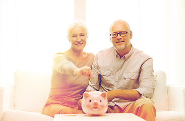 Image showing senior couple with money and piggy bank at home