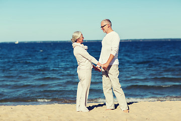 Image showing happy senior couple holding hands on summer beach