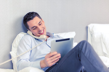 Image showing businessman with tablet pc and phone in hotel room