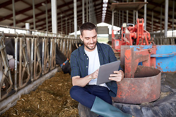 Image showing young man with tablet pc and cows on dairy farm