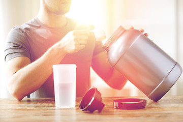 Image showing close up of man with protein shake bottle and jar