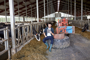 Image showing young man with tablet pc and cows on dairy farm