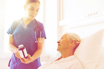 Image showing nurse giving medicine to senior woman at hospital