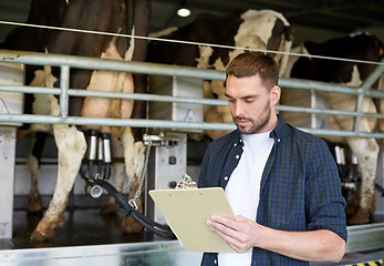 Image showing man with clipboard and milking cows on dairy farm