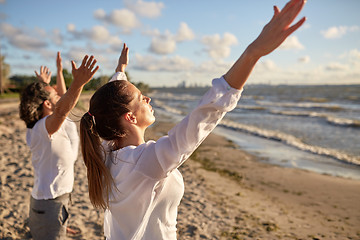 Image showing group of people making yoga or meditating on beach