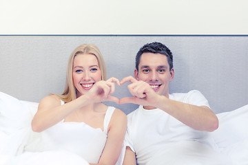 Image showing smiling couple showing heart with hands