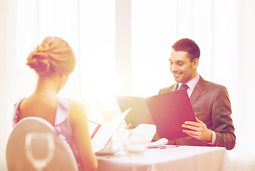 Image showing smiling young man looking at menu at restaurant