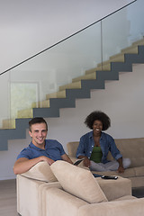 Image showing multiethnic couple relaxing at  home with tablet computers