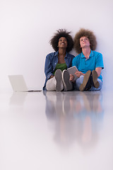 Image showing multiethnic couple sitting on the floor with a laptop and tablet