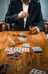 Image showing The man, chips for gamblings, drink and playing cards