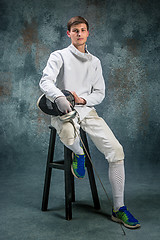 Image showing The man wearing fencing suit with sword against gray