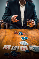 Image showing The man, chips for gamblings, drink and playing cards