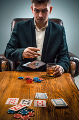 Image showing The man, chips for gamblings, drink and playing cards