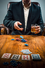 Image showing The man, chips for gamblings, drink and playing cards