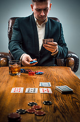 Image showing The man, chips for gamblings, drink and playing cards