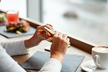Image showing woman eating salmon panini sandwich at restaurant