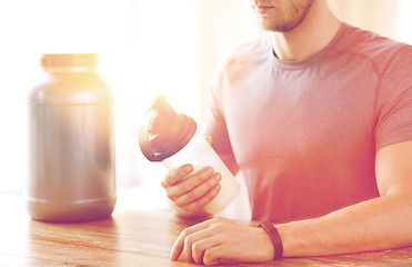 Image showing close up of man with protein shake bottle and jar