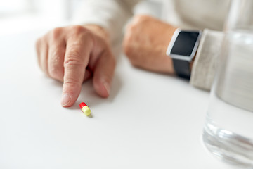 Image showing close up of old man hand with pill and smart watch