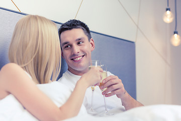 Image showing smiling couple with champagne glasses in bed