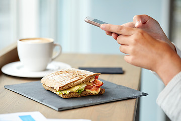 Image showing panini sandwich and woman with smartphone at cafe