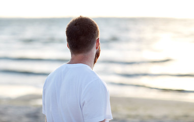 Image showing young man in white t-shirt on beach looking at sea