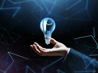 Image showing businessman hand with bulb over dark background