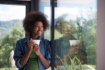 Image showing African American woman drinking coffee looking out the window