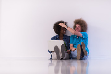 Image showing multiethnic couple sitting on the floor with a laptop and tablet