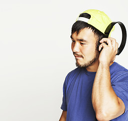 Image showing young asian man in hat and headphones listening music on white b