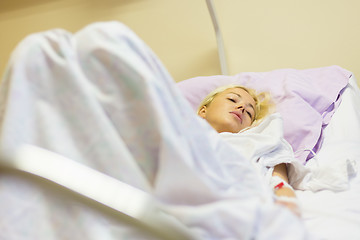 Image showing Bedridden female patient recovering after surgery in hospital care.