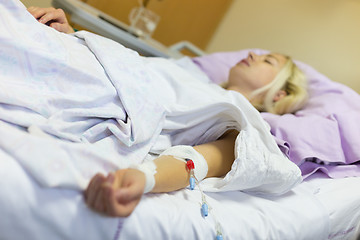 Image showing Bedridden female patient recovering after surgery in hospital care.