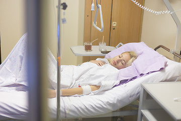 Image showing Bedridden female patient recovering after surgery in hospital care.