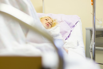 Image showing Bedridden female patient recovering after surgery in hospital care.