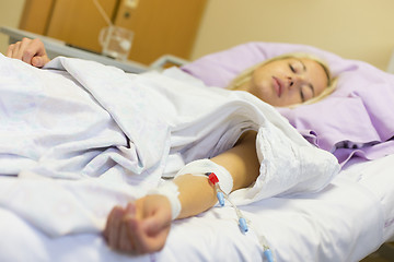 Image showing Bedridden female patient recovering after surgery in hospital care.