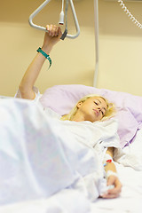 Image showing Bedridden female patient recovering after surgery in hospital care.