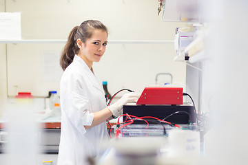 Image showing Life science researcher setting voltege on power supply to run electrophoresis.