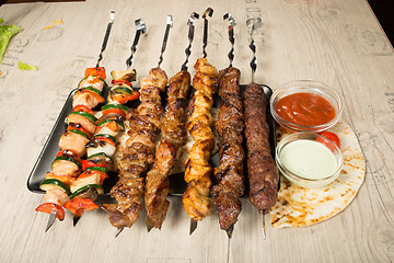 Image showing set shashlik. kebab skewer, black rectangular plate. sauce and onions
