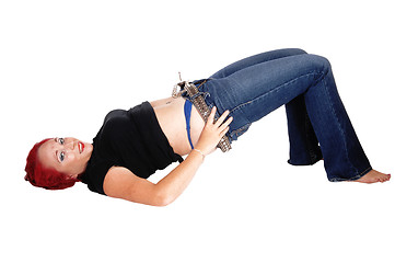 Image showing Woman lying on floor pulling jeans up.