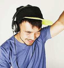 Image showing young asian man in hat and headphones listening music on white b