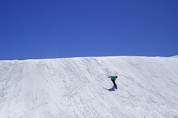 Image showing Snowboarder downhill in terrain park and blue clear sky at ski r