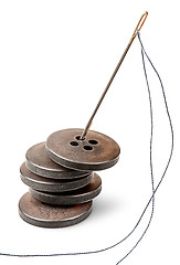 Image showing Stack of old buttons and needle with thread