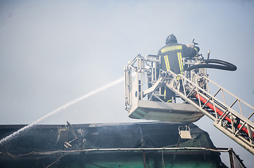 Image showing Firefighters in action fighting, extinguishing fire, in smoke.