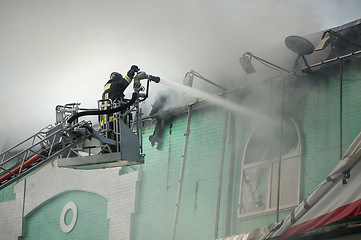 Image showing Firefighters in action fighting, extinguishing fire, in smoke.