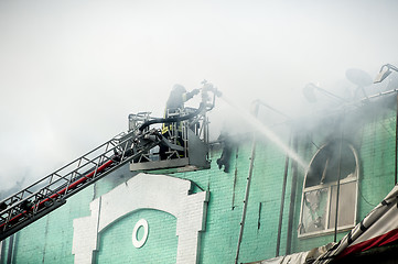 Image showing Firefighters in action fighting, extinguishing fire, in smoke.