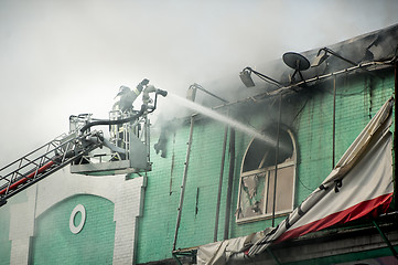 Image showing Firefighters in action fighting, extinguishing fire, in smoke.