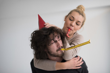 Image showing couple in party hats blowing in whistle